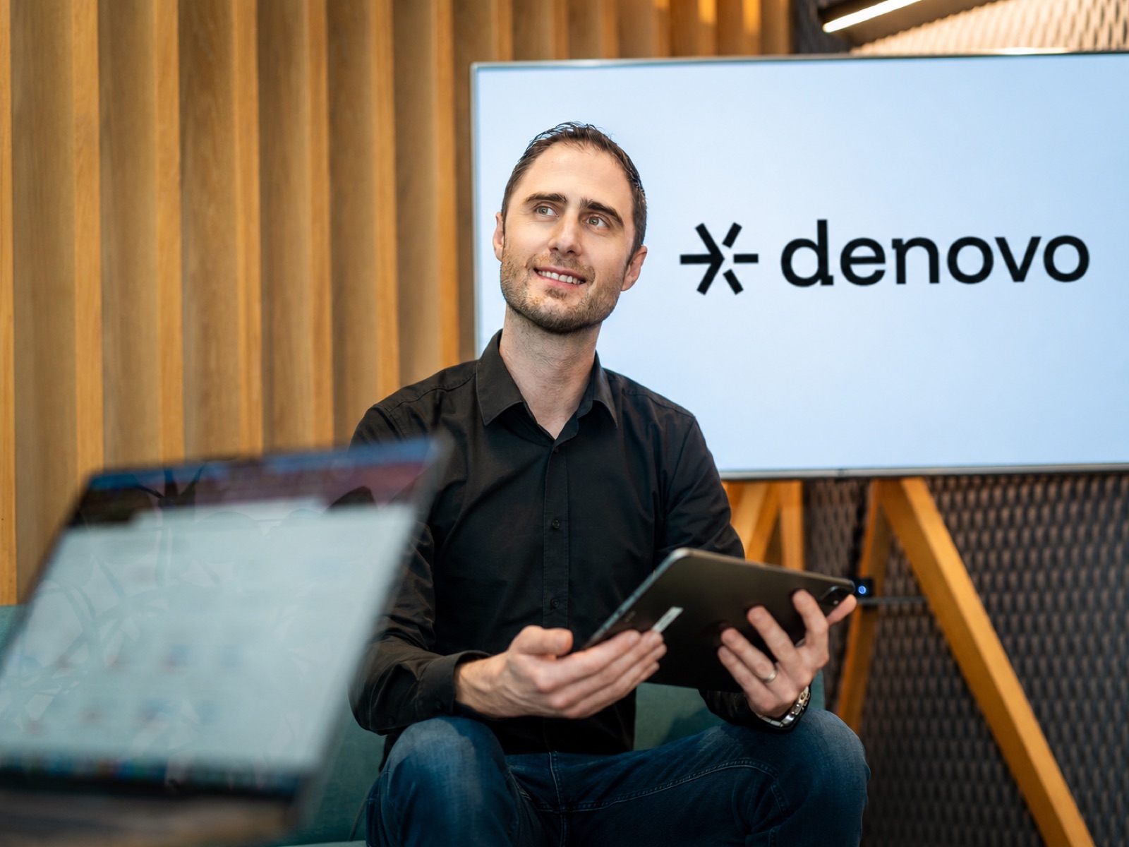Mattias Rauter with a tablet in front of a Denovo screen